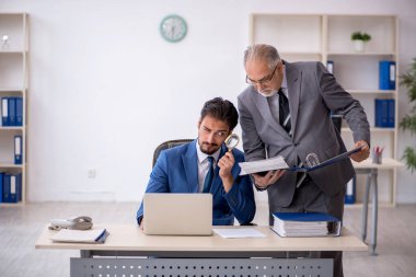 Eski patron ve genç çalışan işyerinde çalışıyor.