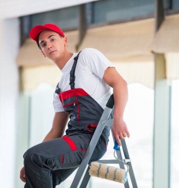 Genç ressam inşaat konseptiyle tavanı boyuyor.