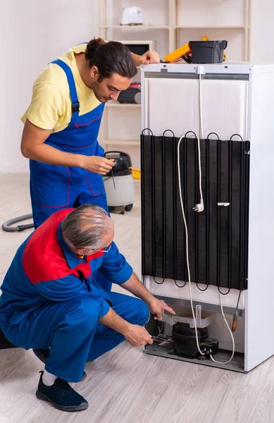 The two contractors repairing fridge at workshop