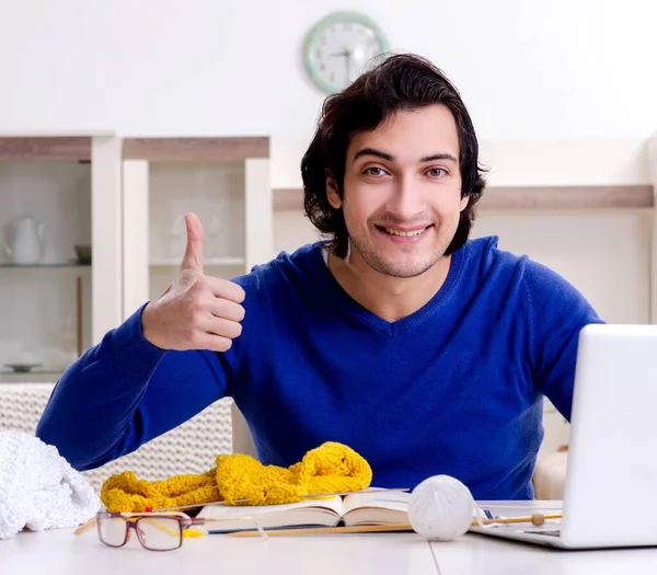 The young good looking man knitting at home