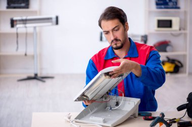 Genç tamirci atölyede ısıtıcıyı tamir ediyor.