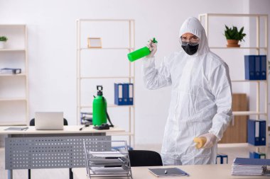 Young contractor disinfecting office during pandemic