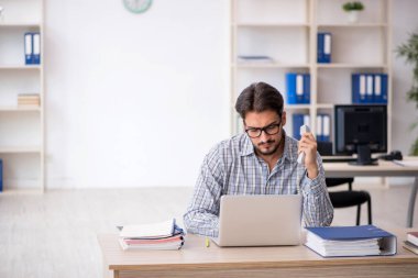 Genç erkek çalışan işyerinde oturuyor.