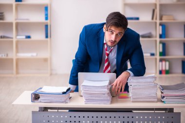 Genç erkek çalışan işyerinde aşırı çalışmaktan memnun değil.