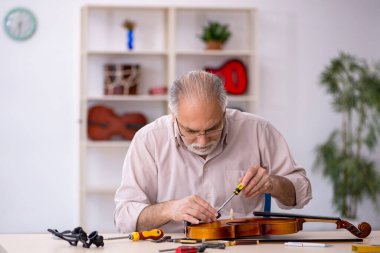 Eski tamirci atölyede müzik aletlerini tamir ediyor.