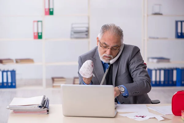 Old businessman employee cutting his hand at workplace