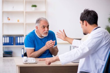 Yaşlı hasta genç erkek doktoru ziyaret ediyor.