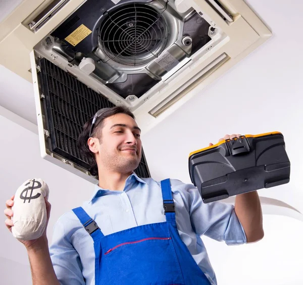 The young repairman repairing ceiling air conditioning unit