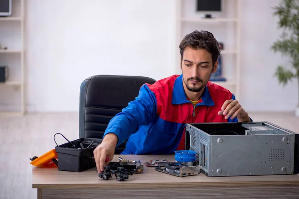 Young repairman repairing computer at workshop