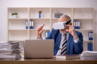 Ofiste sanal gözlük takan yaşlı işadamı.