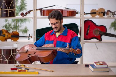 İçeride müzik aletlerini tamir eden genç bir adam.