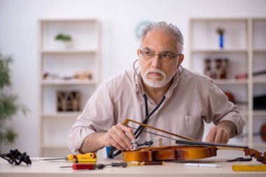 Eski tamirci atölyede müzik aletlerini tamir ediyor.