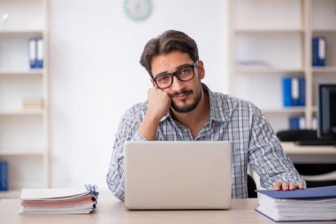 Genç erkek çalışan işyerinde oturuyor.