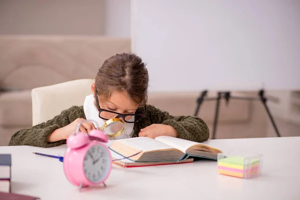 Young small girl studying at home in time management concept