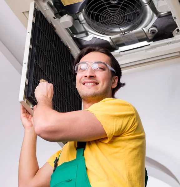 The young repairman repairing ceiling air conditioning unit