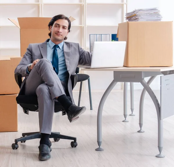 The young man employee with boxes in the office