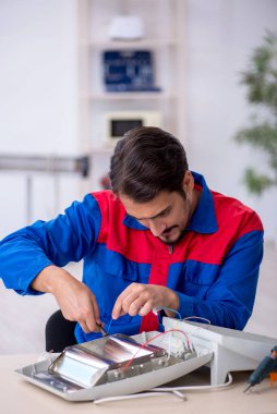 Genç tamirci atölyede ısıtıcıyı tamir ediyor.