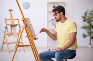 Genç erkek ressam evde resim yapmaktan hoşlanıyor.