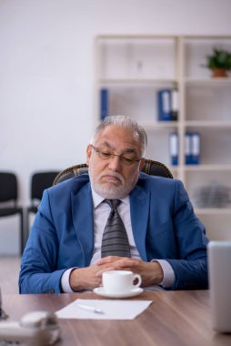 Eski işadamı teneffüste kahve içiyor.