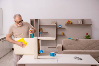 Evde ev işi yapan yaşlı bir adam.