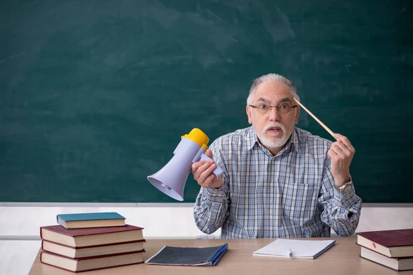 教室でメガホンを握る高齢男性教師 — ストック写真