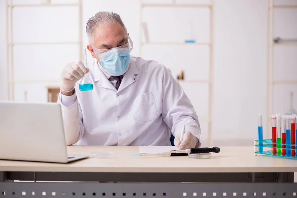 Old chemist working in the lab during pandemic