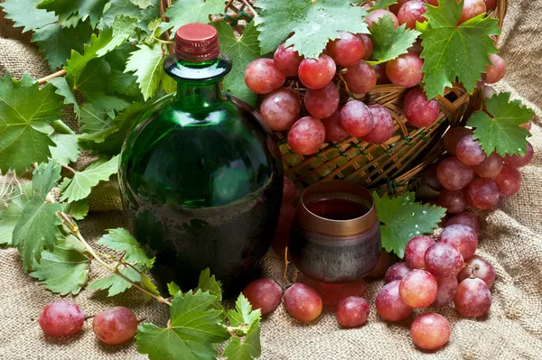 Вино и красный виноград с листьями в корзине — стоковое фото