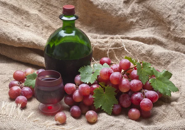 Víno a červené hroznové listy v košíku — Stock fotografie