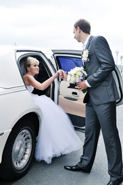 Young Caucasian happy woman in white gorgeous wedding gown sitting in car — Stock Photo, Image