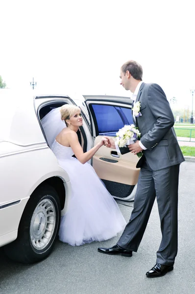 Young Caucasian happy woman in white gorgeous wedding gown sitting in car — Stock Photo, Image