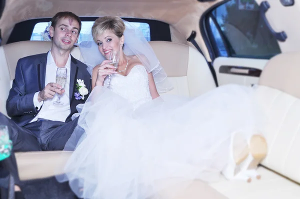 Young Caucasian happy woman in white gorgeous wedding gown sitting in car — Stock Photo, Image