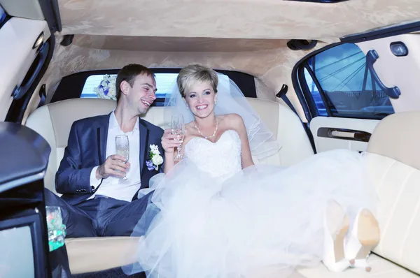 Frischvermählte trinken Champagner in ihrer Limousine — Stockfoto