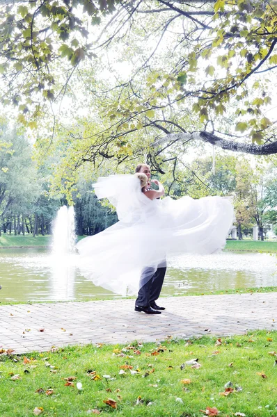 Wedding shot of bride and groom embracing in park — Stock Photo, Image