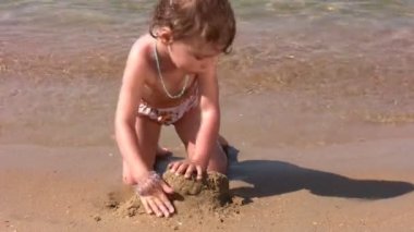 küçük kız sahilde kum ile oynamak
