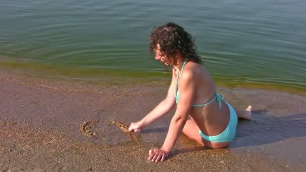 Chica dibujo corazón en la playa — Vídeo de stock