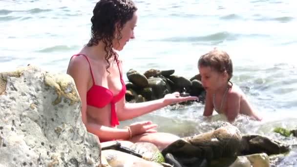 Мать с девушкой на каменном пляже — стоковое видео