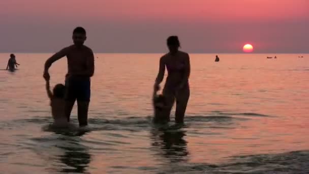 Silhouette famiglia di quattro persone sul mare al tramonto — Video Stock