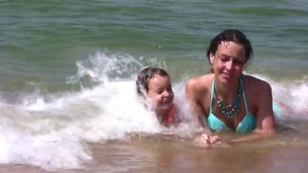 Mother with little girl on splashing beach — Stock Video