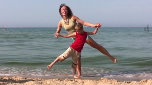 Madre e hijo de pie en una pierna en la playa — Vídeo de stock