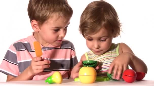 Брат с сестрой с пластиковыми фруктами — стоковое видео