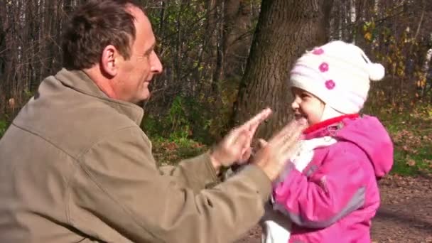 Senior with little girl in autumn park play by hands — Stock Video