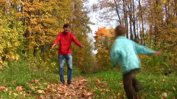 Сын бежит к отцу в осенний парк — стоковое видео