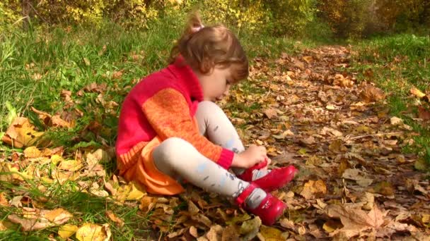 Kleines Mädchen mit Schuhen im Herbstpark — Stockvideo