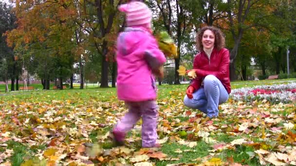 Mutter mit kleinem Mädchen wirft Herbstblätter. — Stockvideo