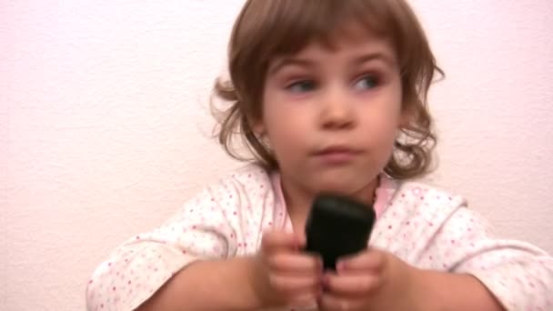 Девочка нажимает на кнопки и разговаривает по телефону — стоковое видео