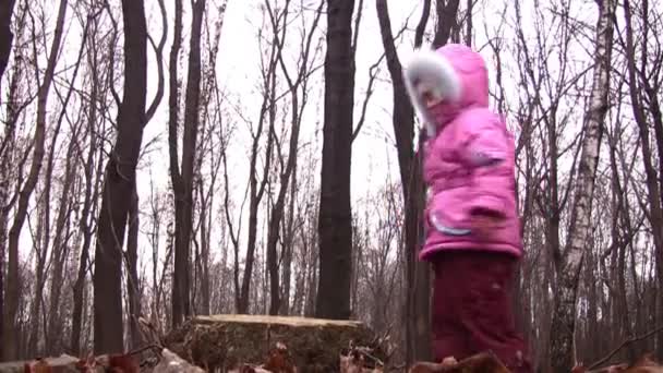 Klein meisje springen van stub in winter park — Stockvideo