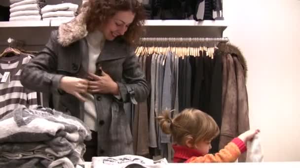 Madre con niña intenta encajar la ropa en la tienda — Vídeo de stock