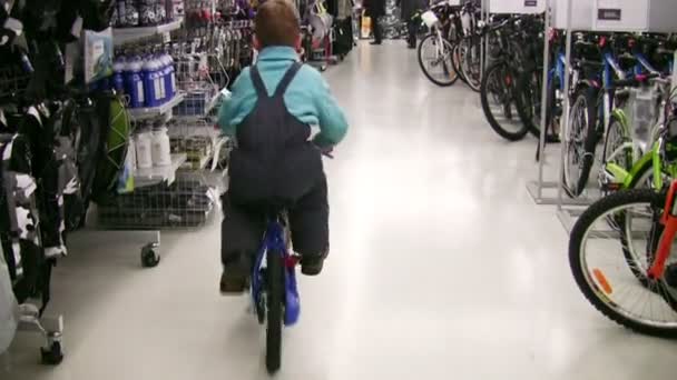 Behind boy on bicycle in shop — Stock Video