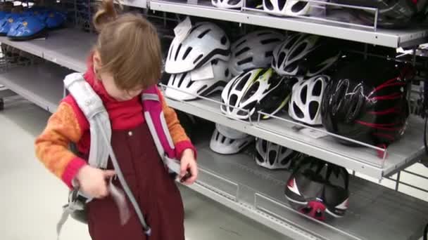 Bambina con zaino in negozio, caschi bici — Video Stock