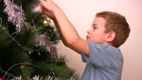 El muchacho cuelga el juguete del árbol de piel en el árbol de Navidad — Vídeos de Stock
